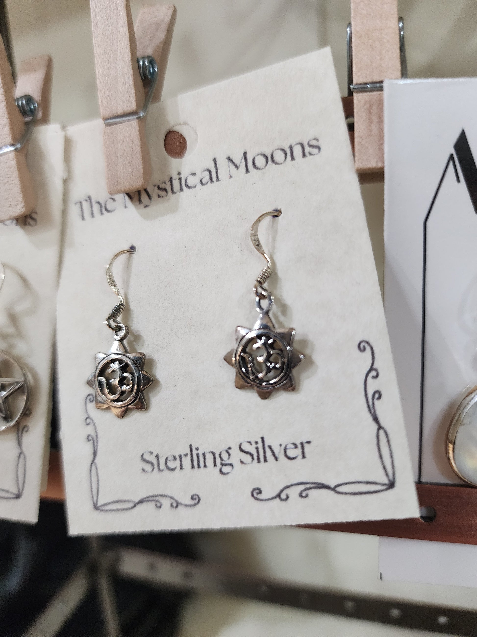 Sterling silver earrings featuring a radiant sun with the Om symbol at the center, displayed on a white background. Perfect for spiritual radiance, peace, and sacred style.