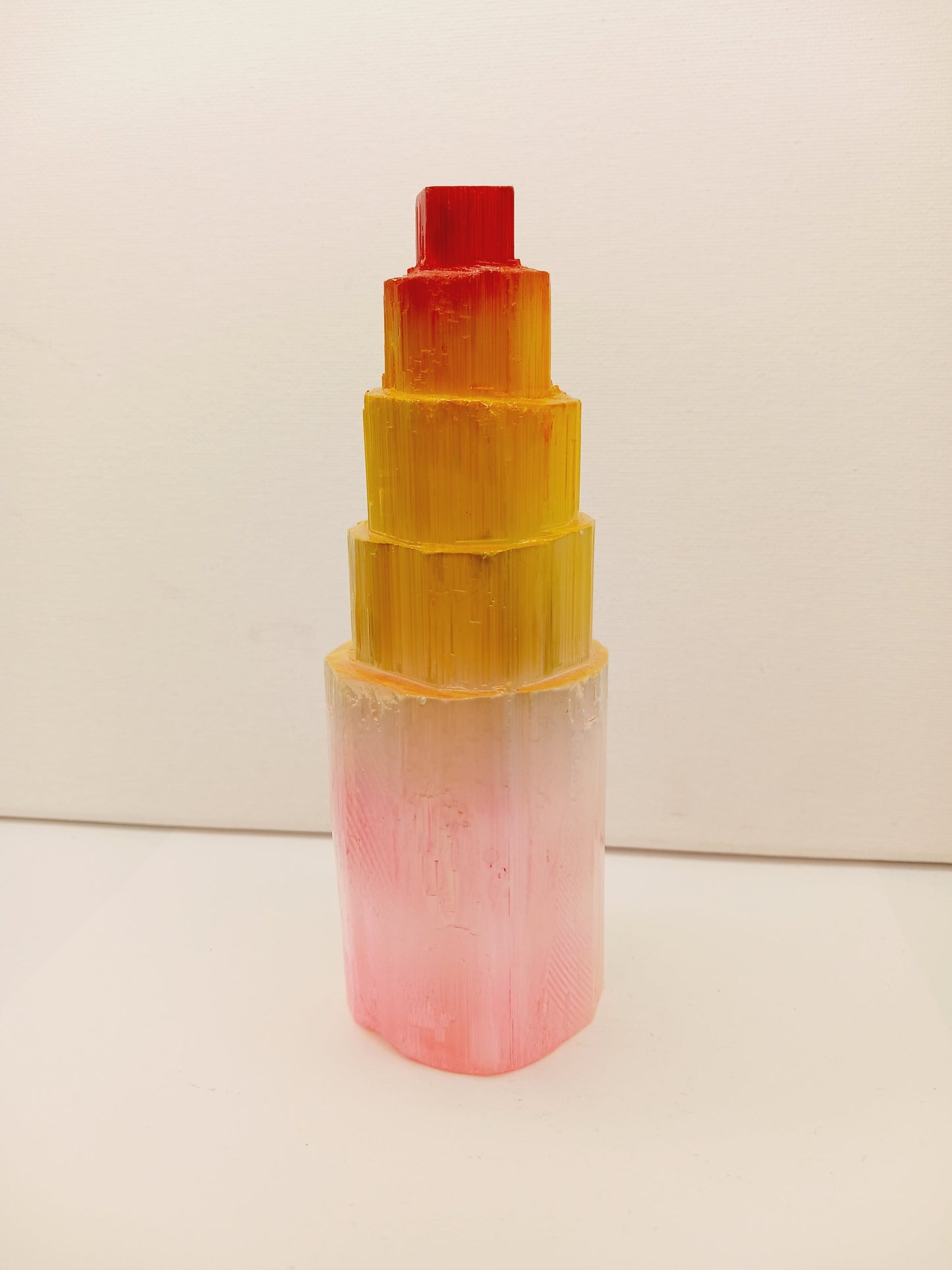 Rainbow selenite tiered tower, polished with a vibrant rainbow sheen and step-like design, displayed on a white background.