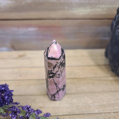 Hand-carved Rhodonite tower featuring vibrant pink hues with bold black veining, displayed on a white background.