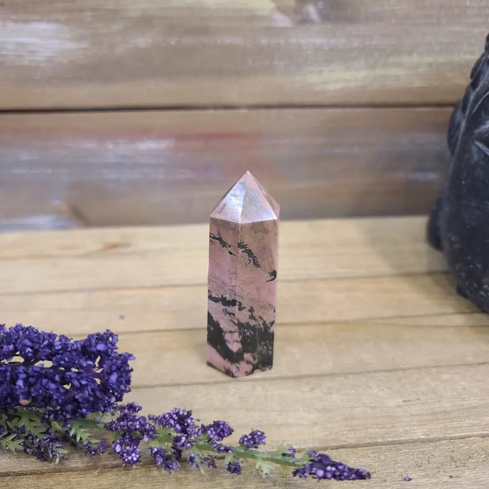 Hand-carved Rhodonite tower featuring vibrant pink hues with bold black veining, displayed on a white background.