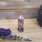 Hand-carved Rhodonite tower featuring vibrant pink hues with bold black veining, displayed on a white background.
