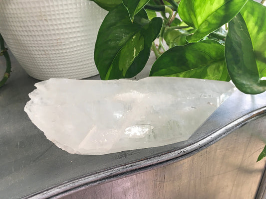 Natural rough quartz point crystal with clear, unpolished surfaces and unique shape, displayed on a white background. Perfect for energy amplification, cleansing, and spiritual work.