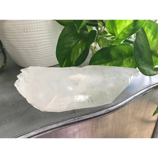 Natural rough quartz point crystal with clear, unpolished surfaces and unique shape, displayed on a white background. Perfect for energy amplification, cleansing, and spiritual work.