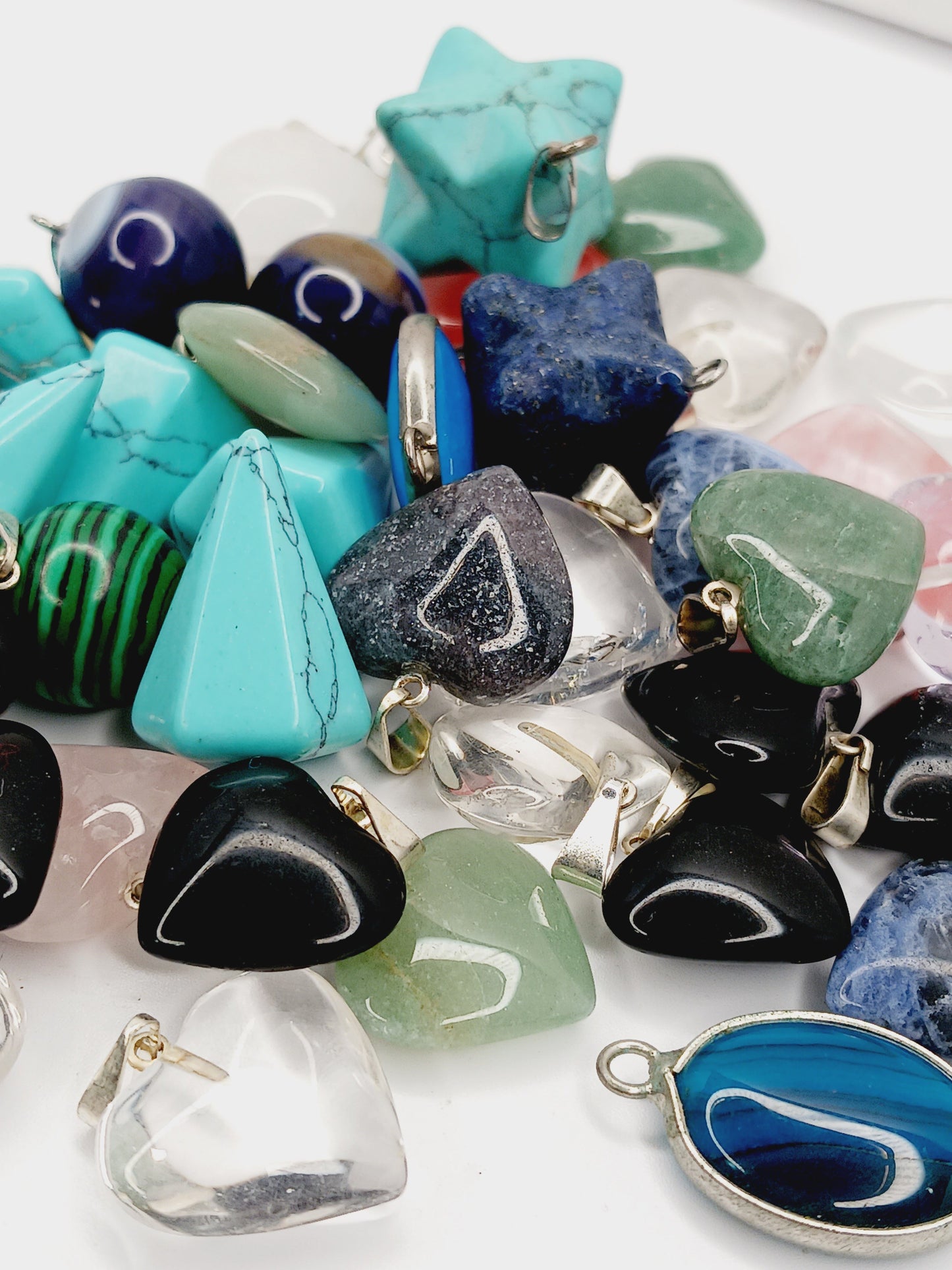 Assorted small stone pendants, each with polished gemstones in various colors and shapes, displayed on a white background.
