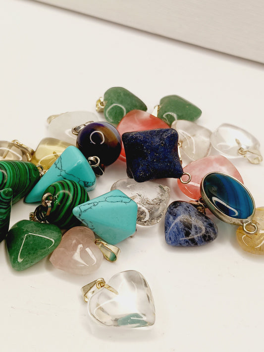 Assorted small stone pendants, each with polished gemstones in various colors and shapes, displayed on a white background.
