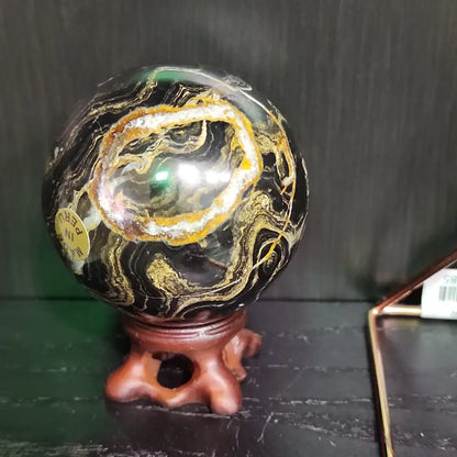 Hand-polished Stromatolite fossil sphere, approximately 2.5 inches in diameter, featuring swirling earthy fossilized patterns, displayed on a white background.
