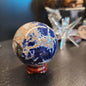 Hand-polished Sunset Sodalite sphere featuring vibrant blue sodalite with glowing orange sunstone streaks, displayed on a white background.