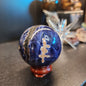 Hand-polished Sunset Sodalite sphere featuring vibrant blue sodalite with glowing orange sunstone streaks, displayed on a white background.
