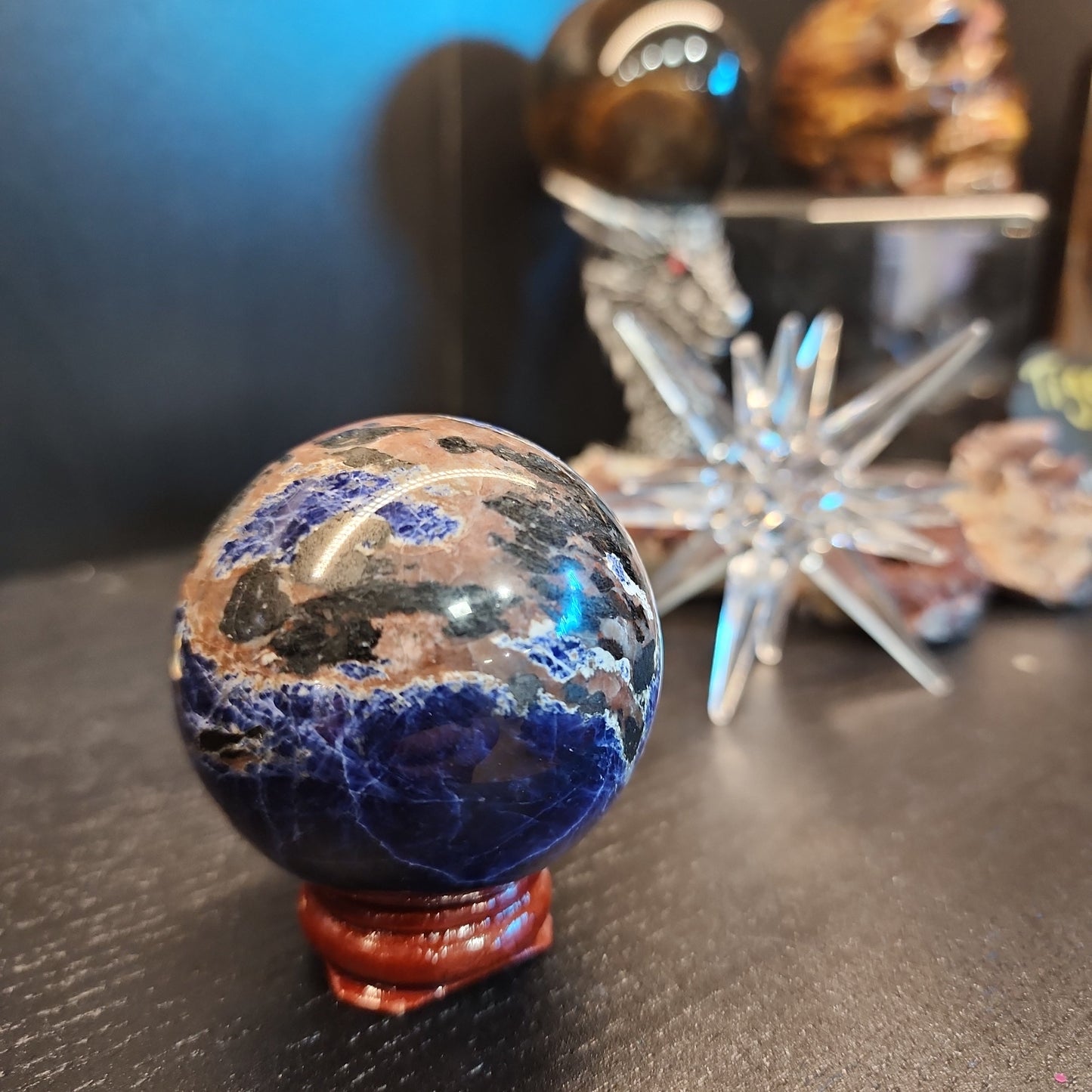 Hand-polished Sunset Sodalite sphere featuring vibrant blue sodalite with glowing orange sunstone streaks, displayed on a white background.