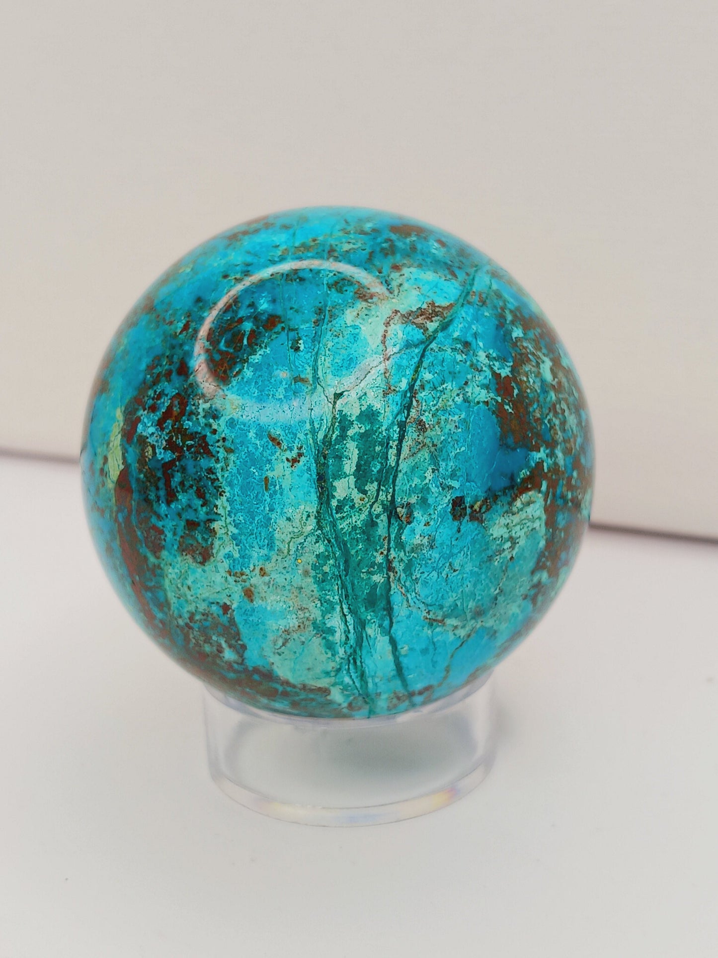 Turquoise sphere with vibrant blue-green color and natural veining, displayed on a white background.