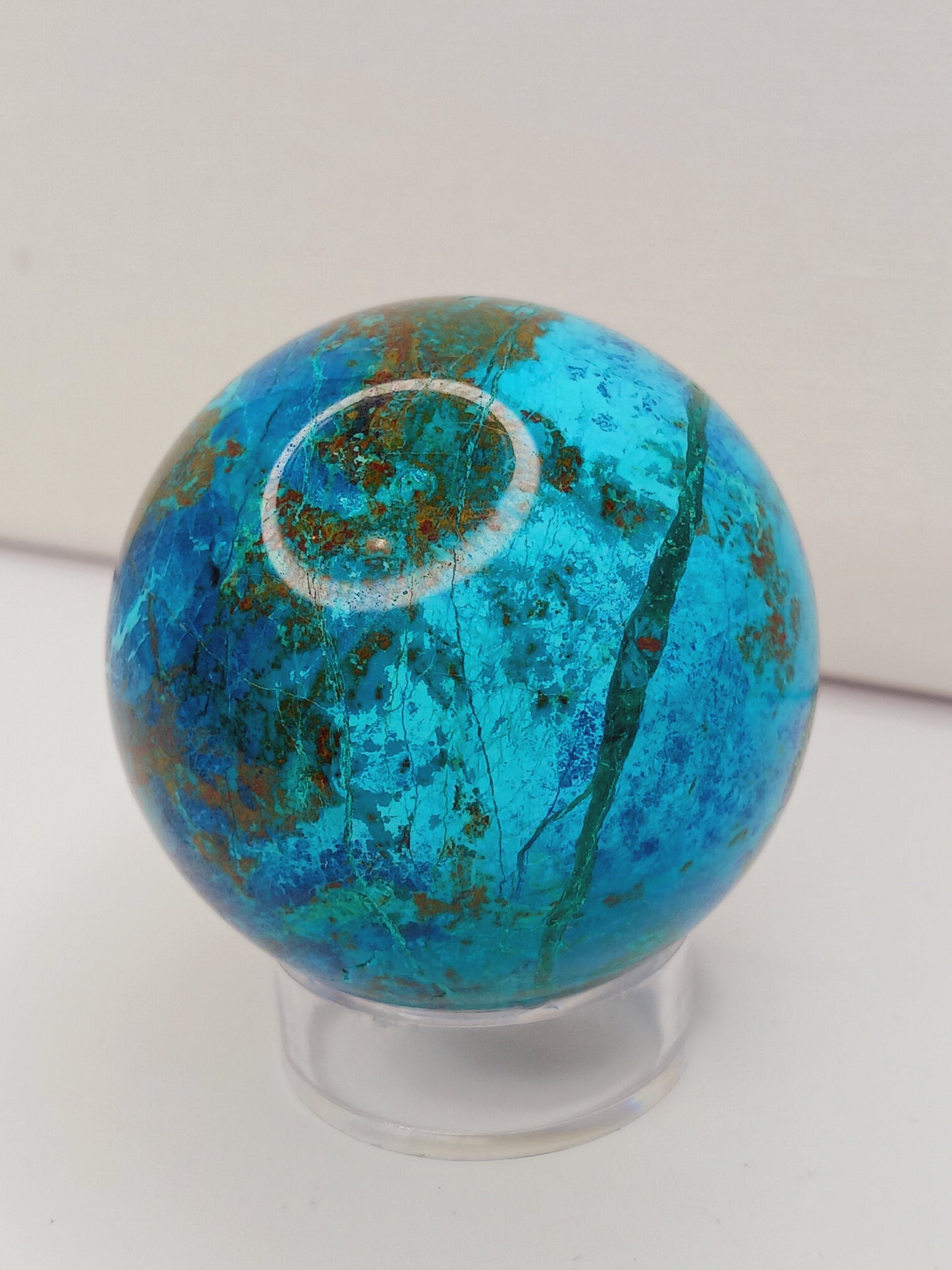 Turquoise sphere with vibrant blue-green color and natural veining, displayed on a white background.