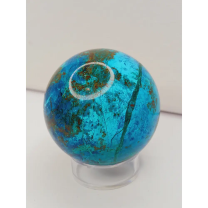 Turquoise sphere with vibrant blue-green color and natural veining, displayed on a white background.
