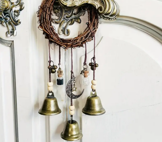 Decorative wall hanging with bells and a moon charm against a white background