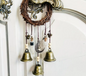 Decorative wall hanging with bells and a moon charm against a white background